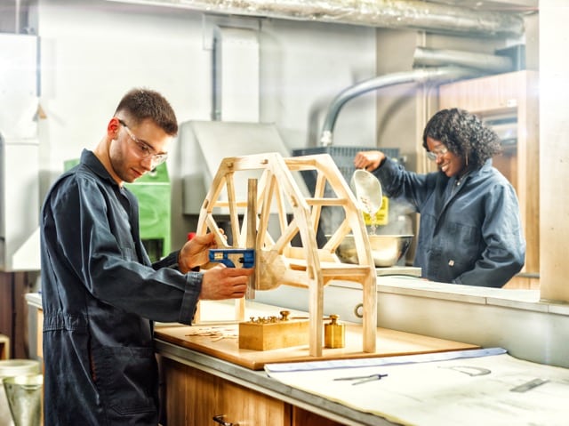 Une étudiante et un étudiant s'affairent a construire des structures de bois