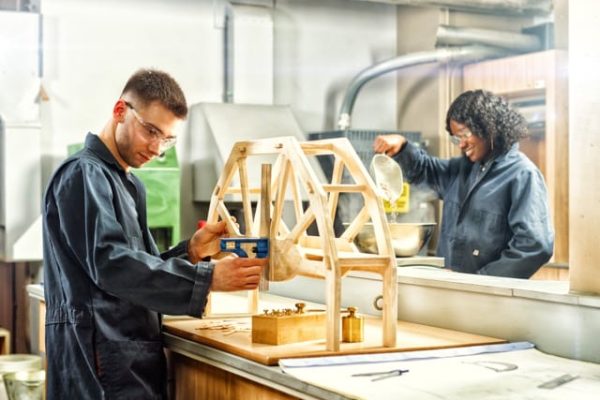 Une étudiante et un étudiant s'affairent a construire des structures de bois